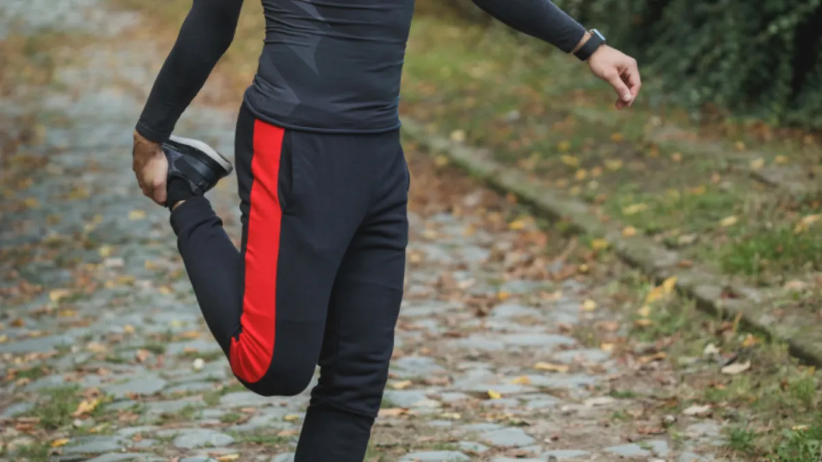Deportista estirando el cuádriceps en un camino antes de entrenar