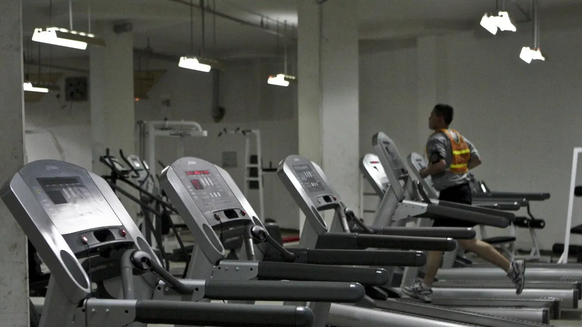 Fila de cintas de correr en un gimnasio con una persona corriendo al fondo