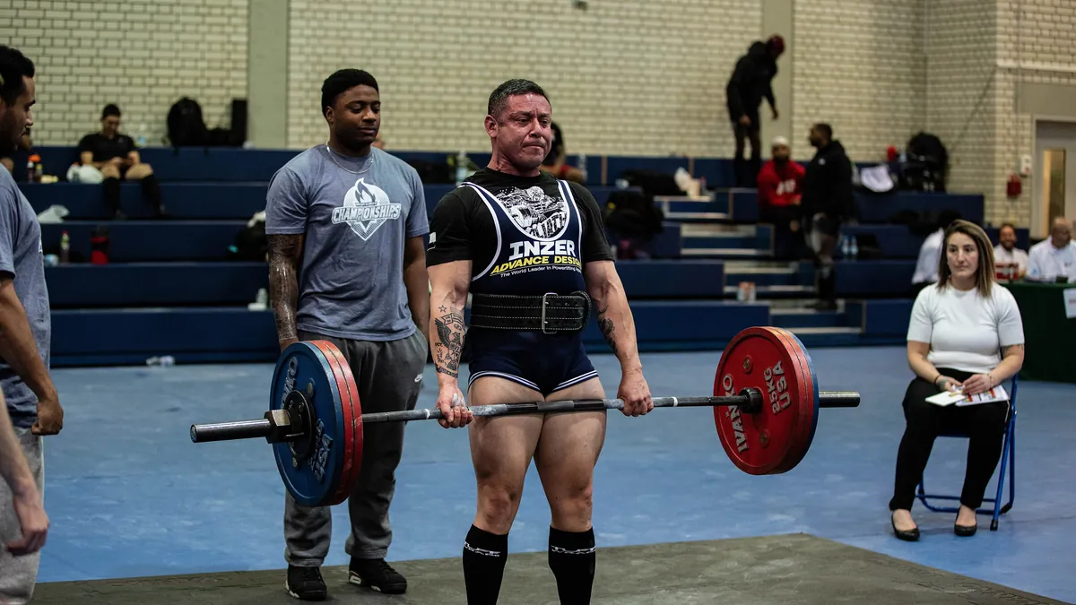 Levantador con cinturón de levantamiento terminando un peso muerto durante una competición de powerlifting
