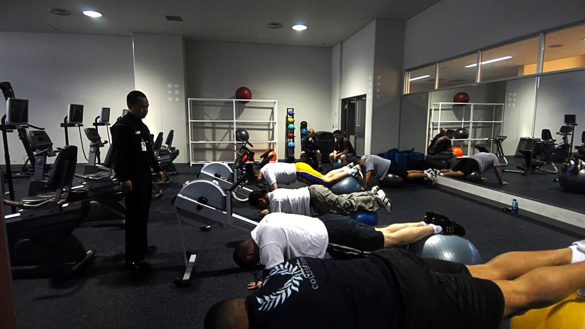 Varias personas tumbadas boca abajo sobre balones de ejercicio en una sesión de fisioterapia lumbar en un gimnasio