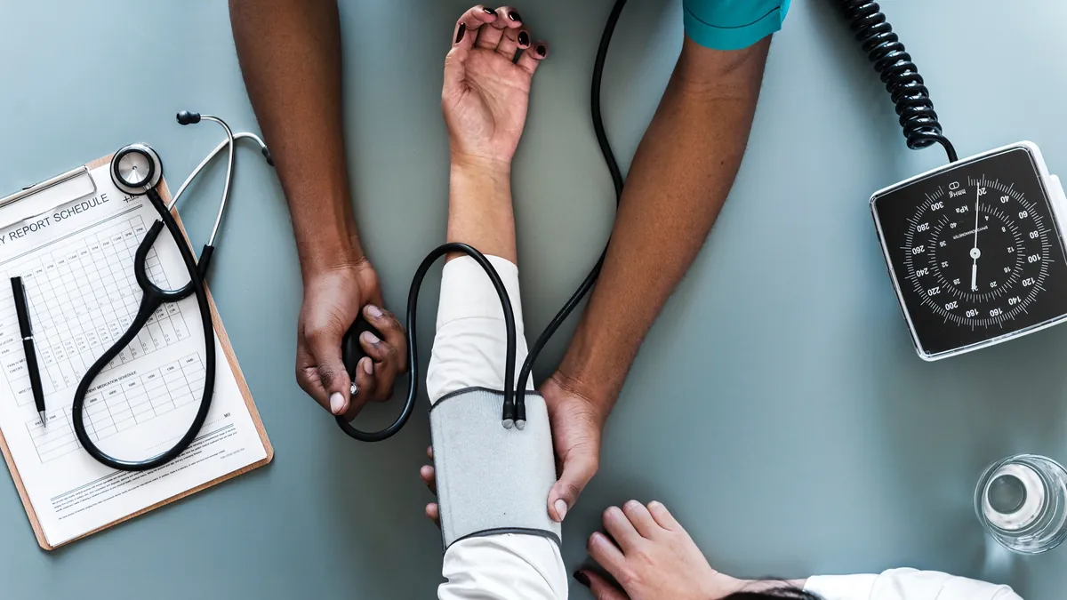 Mesure de la tension artérielle d'un patient avec un brassard, vue de dessus
