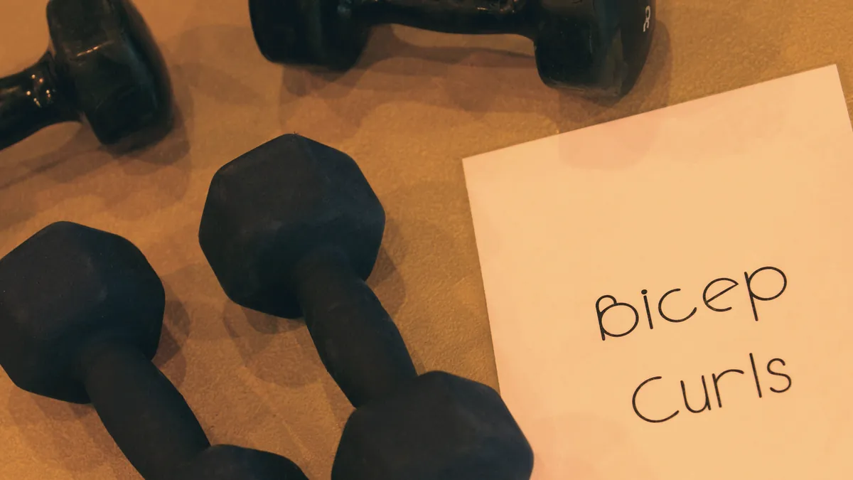 Mancuernas sobre una mesa junto a una nota con las palabras «Bicep Curls»