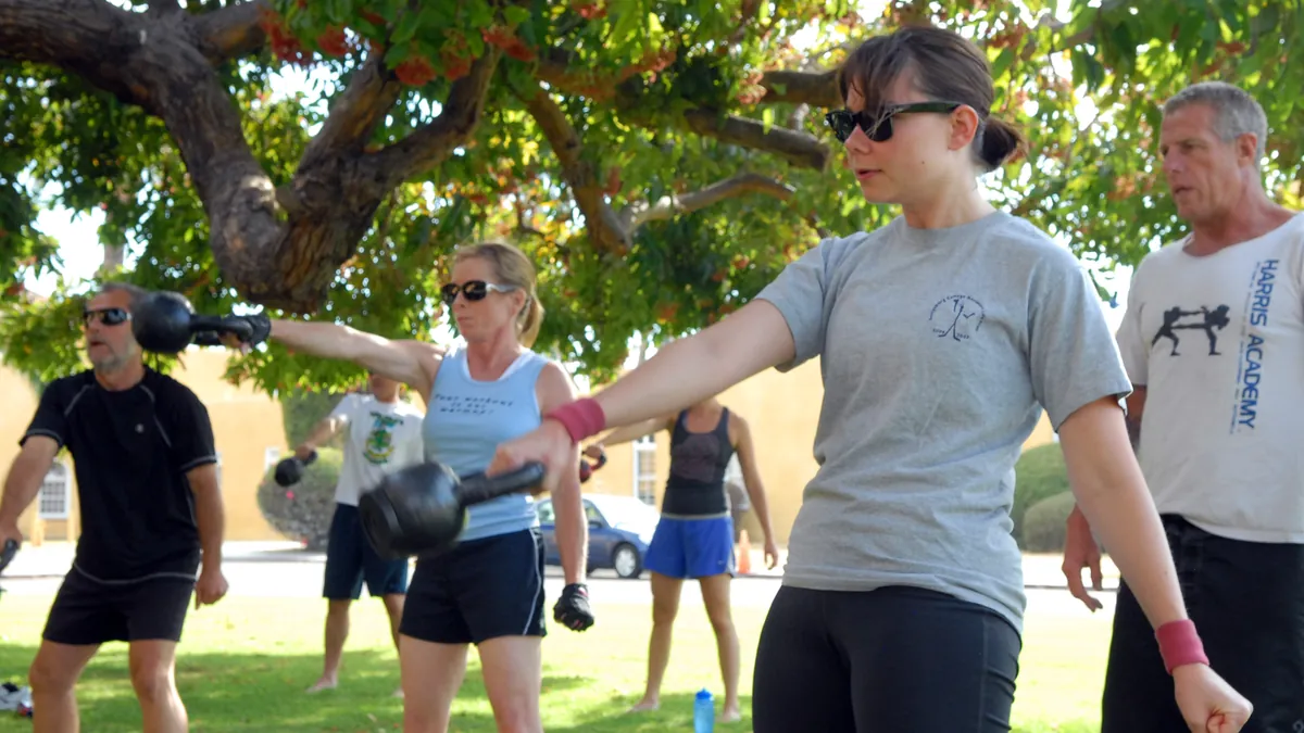 Group of adults of different ages training with kettlebells outdoors