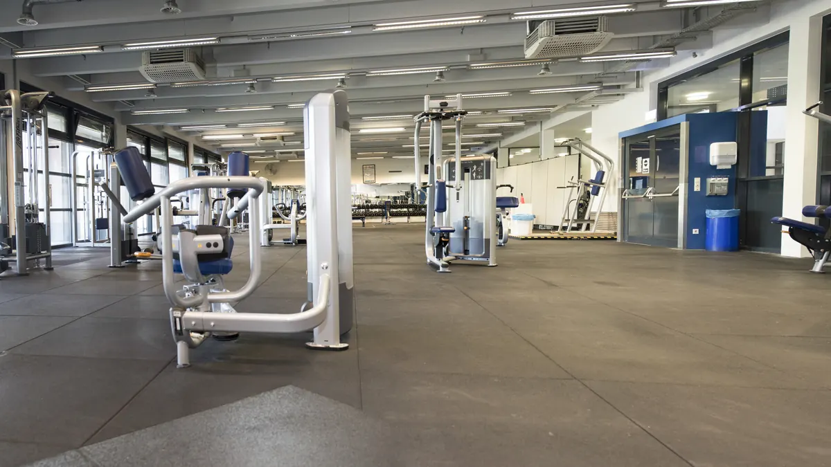Sala de musculación amplia y vacía con máquinas de fuerza y ventanales