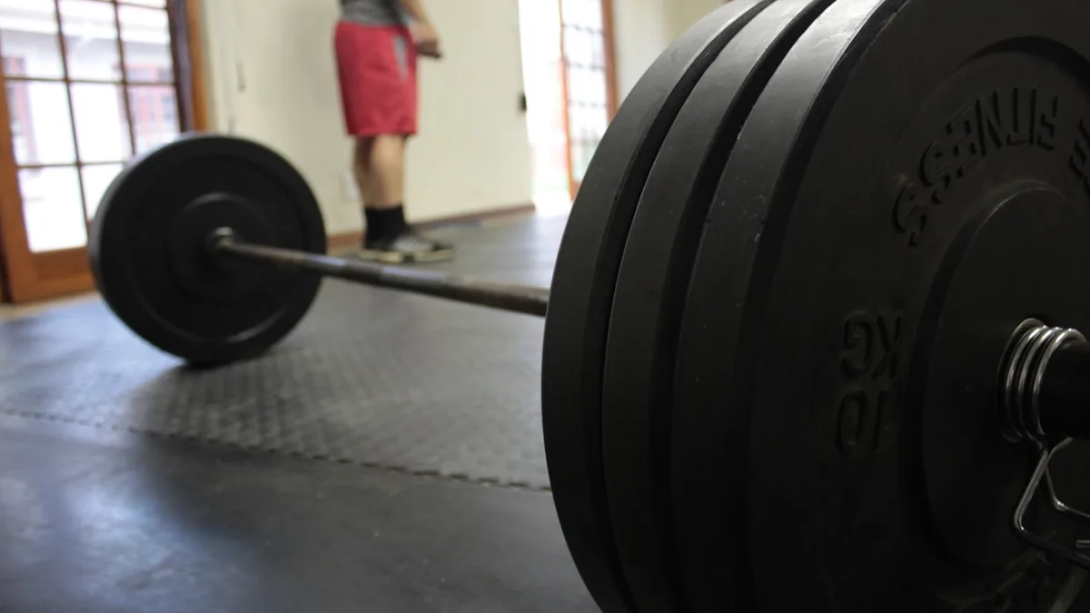 Barra olímpica cargada con discos en el suelo de un gimnasio