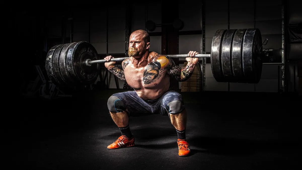 Homme faisant un squat avec une barre chargée dans une salle de sport