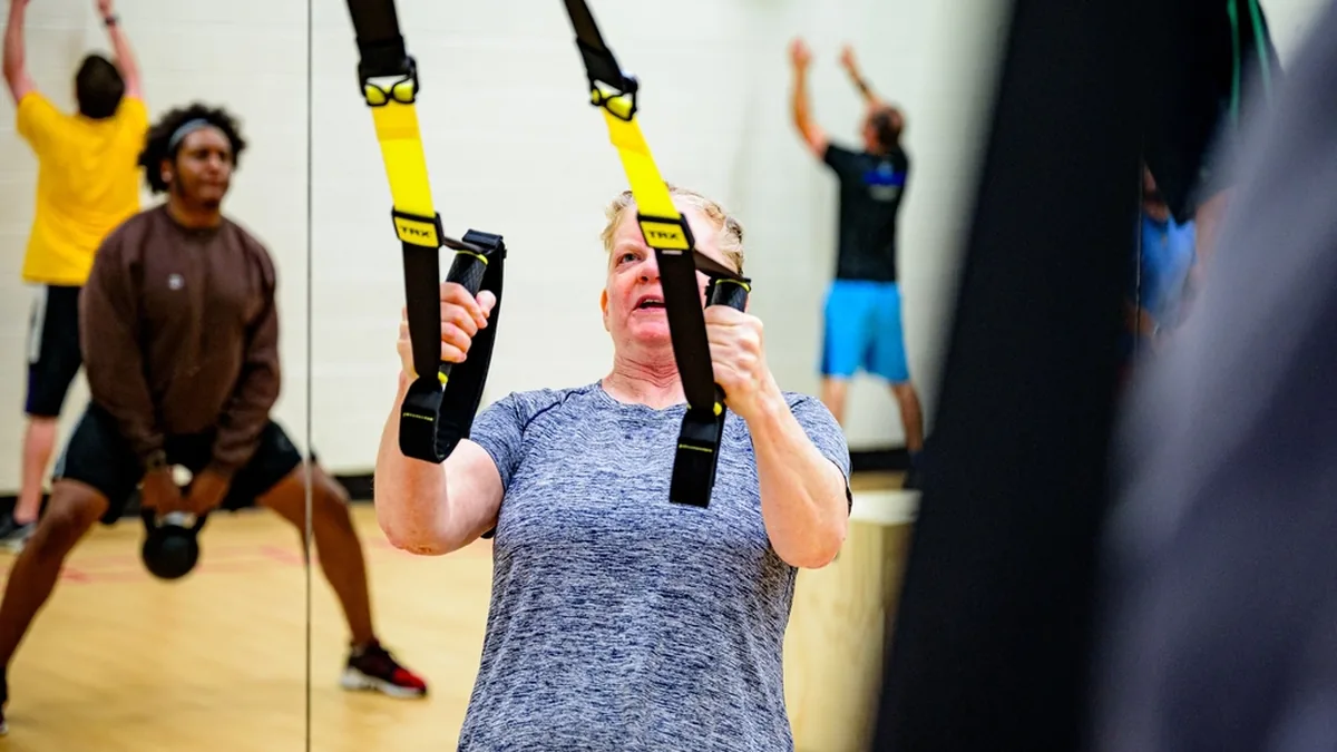 Mujer adulta entrenando con cintas de suspensión en un gimnasio