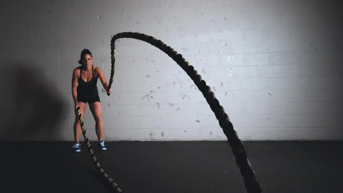 Mujer entrenando con cuerdas de batalla en una sala
