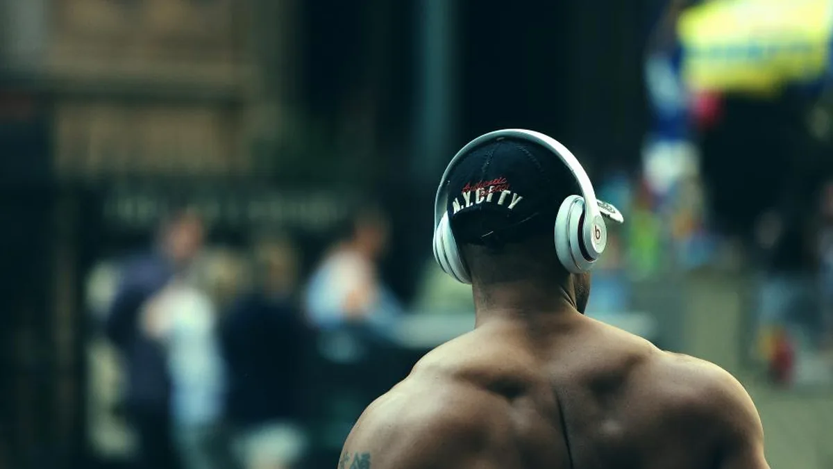 Espalda musculada de un hombre con auriculares en la calle