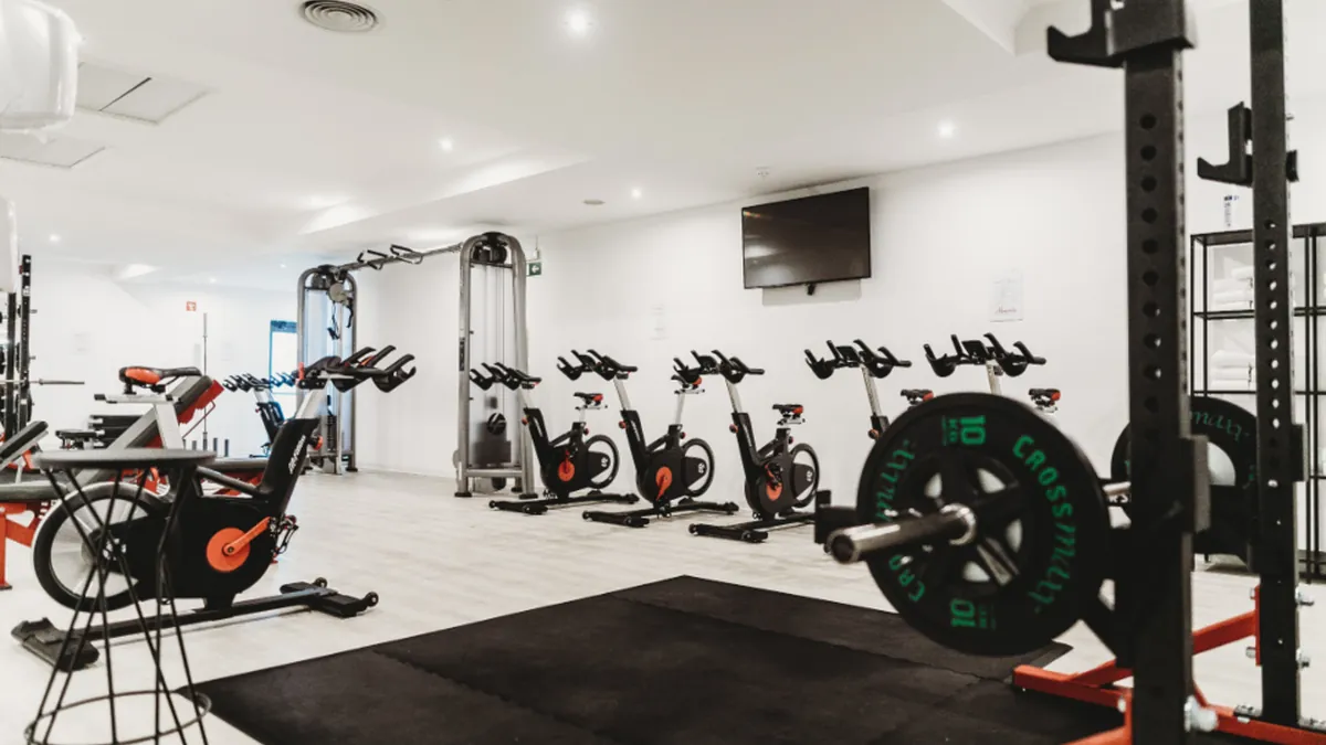 Gimnasio luminoso y vacío con bicicletas estáticas y un rack de sentadillas
